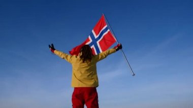 Sırtını Norveç bayrağı ile mavi gökyüzü ile bir adam duruyor. Milli takım için destek.