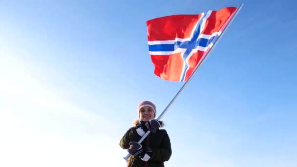 Женщина с флагом Норвегии против голубого неба. Поддержка вентиляторов . — стоковое видео