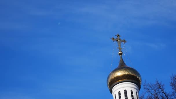 Zlatý kříž na kopuli kostela proti modré obloze — Stock video