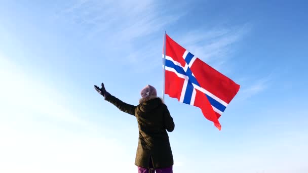 Mujer con la bandera de Noruega contra el cielo azul. Apoyo al ventilador . — Vídeos de Stock