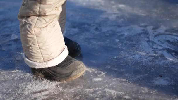 Ett barn går på isen utan skridskor. — Stockvideo