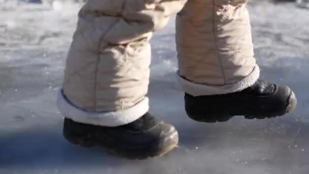 Uma criança caminha no gelo sem patins . — Vídeo de Stock