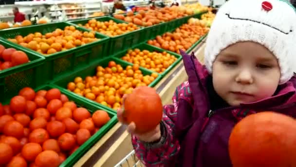 En söt barn väljer frukt i en stormarknad. — Stockvideo