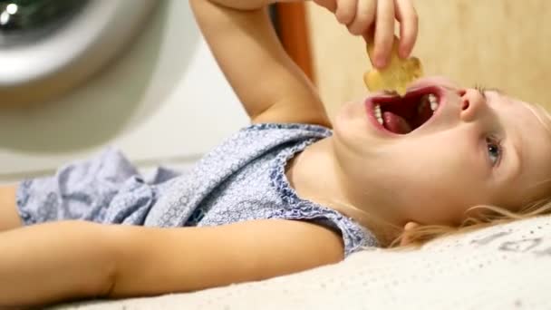 L'enfant se couche sur un lit et mange — Video