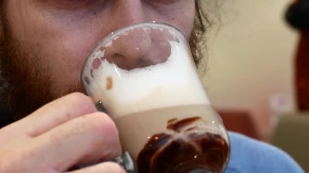 Närbild av en skäggig man dricka cappuccino. — Stockvideo