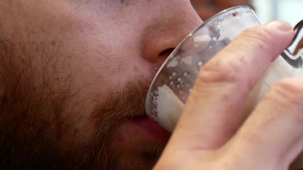 Närbild av en skäggig man dricka cappuccino. — Stockvideo