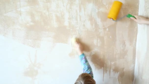 Het meisje helpt bij het doen van reparaties in haar kamer. Het kind schildert de muren met een roller. — Stockvideo