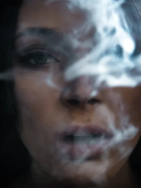Fashion portrait of a beautiful young woman who exhales smoke — Stock Photo, Image