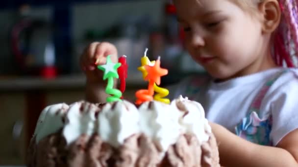 Девушка вставляет и зажигает свечи в торт в течение четырех лет . — стоковое видео