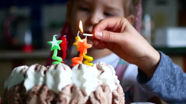 Het meisje wordt ingevoegd en het licht van de kaarsen in haar taart voor vier jaar. — Stockvideo