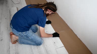 Dreadlocks ile genç bir adam evde Laminant yığar.