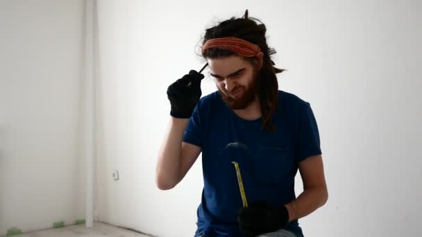 Молодой человек с дредами что-то измеряет рулеткой — стоковое видео