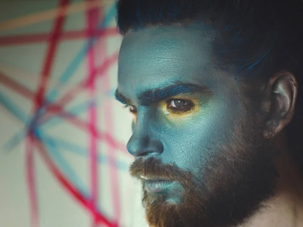 Portrait of a man with a blue make-up on his face. Stage make-up, like an alien, fantasy. — Stock Photo, Image