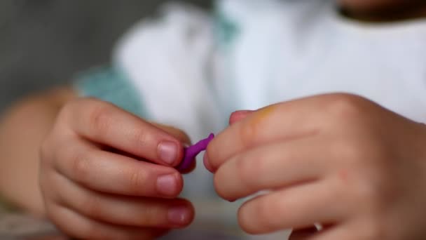 Unknown little girl sitting at the desk sculpts a different figures from made of colored modeling plasticine in the nursery. — Stock Video