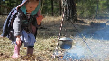 Küçük bir kız üzerinde kamp ateşi ahşap atar. Bağımsızlık ve durum tespiti