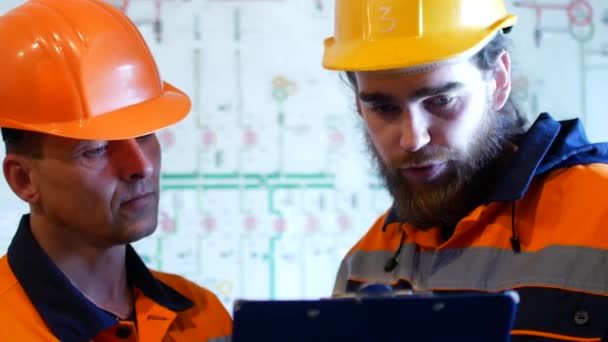 Dos ingenieros en cascos de protección trabajando juntos en el área de la construcción — Vídeo de stock