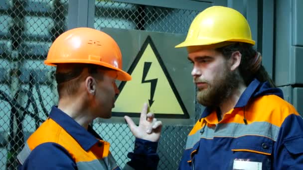 Dois eletricistas na subestação falando no fundo do sinal de perigo — Vídeo de Stock