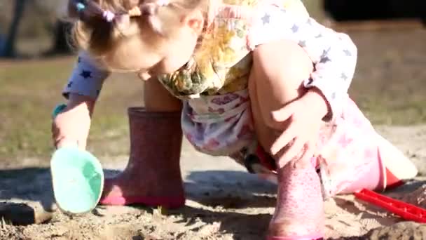 Küçük bir kız kum havuzunda kazıyor. Ukrayna köyde — Stok video