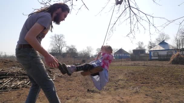 Vater schubst seine Tochter auf der Schaukel und amüsiert sich im Park — Stockvideo