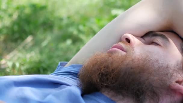 Счастливый молодой человек лежит в траве — стоковое видео