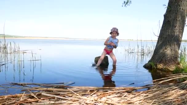 Niña sale del lago, sosteniendo los vestidos — Vídeos de Stock