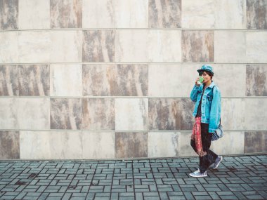 gri duvar arka plan kaldırımlar açık koridor holding sıcak espresso kahve Kupası üzerinde yürüyen kadın.