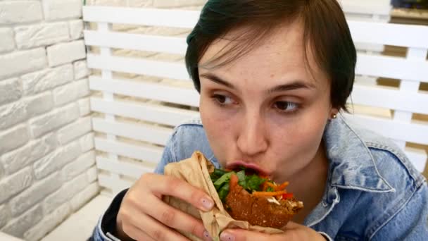 Vrouw eten boterham, zithoek in de buurt van het venster in het café — Stockvideo