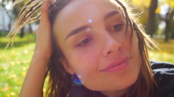 Retrato de una joven con rastas. La chica gira su cabeza al sol y sonríe — Vídeo de stock