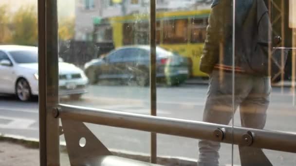 Un homme attend un bus à un arrêt de bus. Il est en retard, regarde sa montre, passe du pied au pied — Video