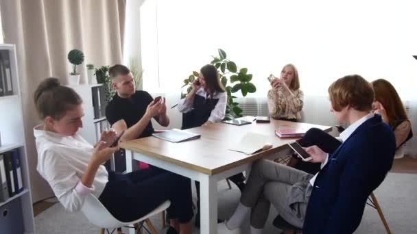 Une équipe de jeunes professionnels est assise à la table et chacun est occupé avec sa propre entreprise. Les gens restent au téléphone, le réalisateur vient gronder tout le monde. — Video