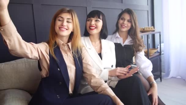 Tre unga flickor sitter i en soffa. Flickvänner tar en selfie. Kvinnor på fest hemma — Stockvideo