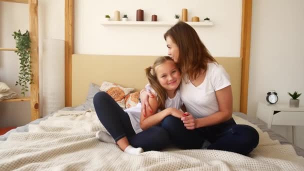 Mom and daughter are teenagers sitting on the bed and talking cute. Family values and trust — Stock Video