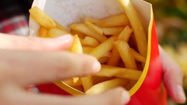 Patates kızartması servisi hazır. Kız paketten patates kızartması alıyor.