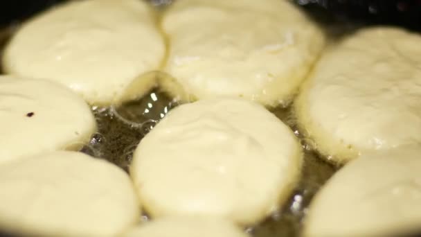 Kleine pannenkoeken worden gebakken in een koekenpan in olie — Stockvideo