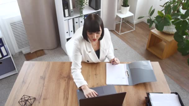 Discusión en el lugar de trabajo. El jefe se sienta frente a un portátil, y dos asistentes lo ayudan. — Vídeos de Stock