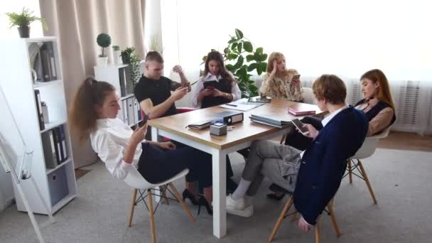 Une équipe de jeunes professionnels est assise à la table et chacun est occupé avec sa propre entreprise. Les gens restent au téléphone, le réalisateur vient gronder tout le monde. — Video