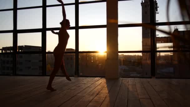 The girl is engaged in modern jazz ballet in a loft studio. A woman is spinning in a sunny room — ストック動画