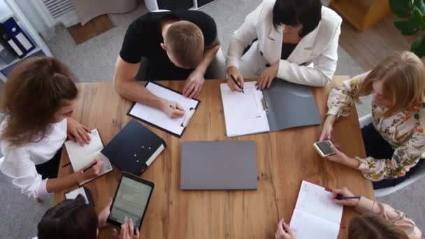 Jovem equipa de negócios em brainstorm. Visão superior, os gerentes escolhem uma estratégia de desenvolvimento de marca — Vídeo de Stock