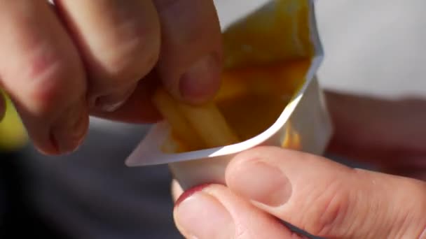 En man doppar pommes frites i senapssås. Närbild av burkar med sås och potatis — Stockvideo