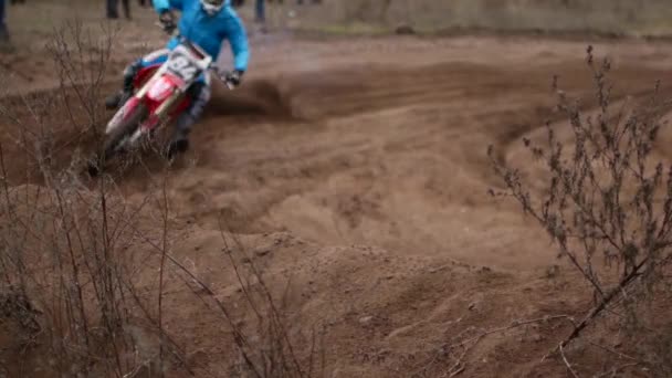 Les compétitions de motocross, les motos roulent sur une piste de terre. Au premier plan l'herbe et le sol, les participants de la compétition en defocus — Video