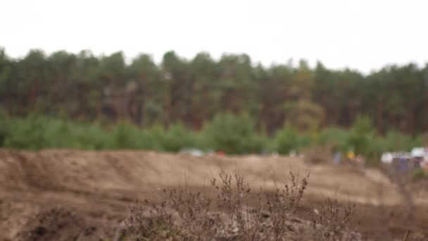 Motokrosové závody, motocykly na prašné dráze. V popředí trávy a půdy, účastníci soutěže v defokusu — Stock video