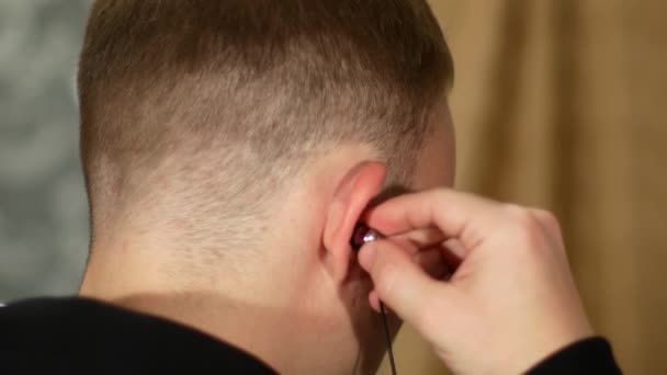 Un jeune homme met des écouteurs dans ses oreilles — Video