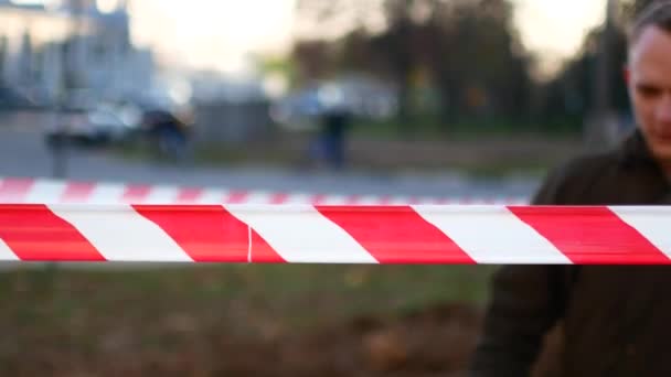 A detective forbids going to the crime scene. The crime scene is fenced with tape and not allowed there — Stock Video