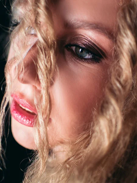 Retrato de una joven y hermosa mujer. Chica contra un fondo oscuro con una sonrisa natural y el pelo rizado . — Foto de Stock