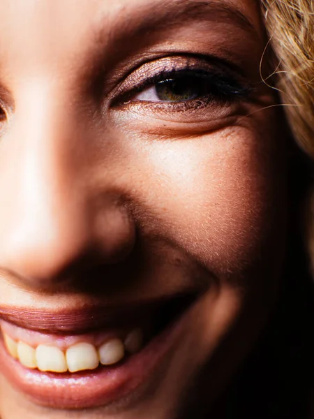 Portret van een mooie jonge vrouw. Meisje tegen een donkere achtergrond met een natuurlijke glimlach en krullend haar. — Stockfoto