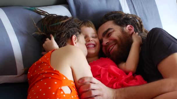 Familia feliz descansando en la cama. Mamá papá e hija ríen y charlan — Vídeos de Stock