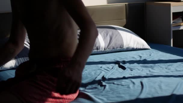 Een man valt op het bed na een douche. Na een zware dag moet je ontspannen. — Stockvideo