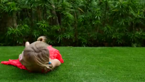Mädchen reitet auf dem grünen Gras. Spaziergang an der frischen Luft, ein Mädchen wälzt sich im Gras — Stockvideo