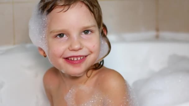 Barnet tar ett bad och leker med skum — Stockvideo