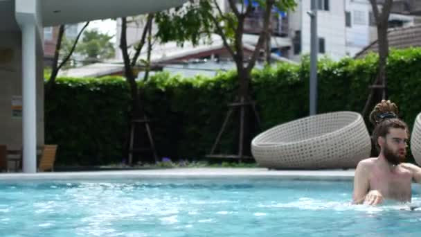 Um homem está dançando e se divertindo na piscina. Um homem se alegra e acena suas mãos porque ele veio para umas férias tão esperadas — Vídeo de Stock